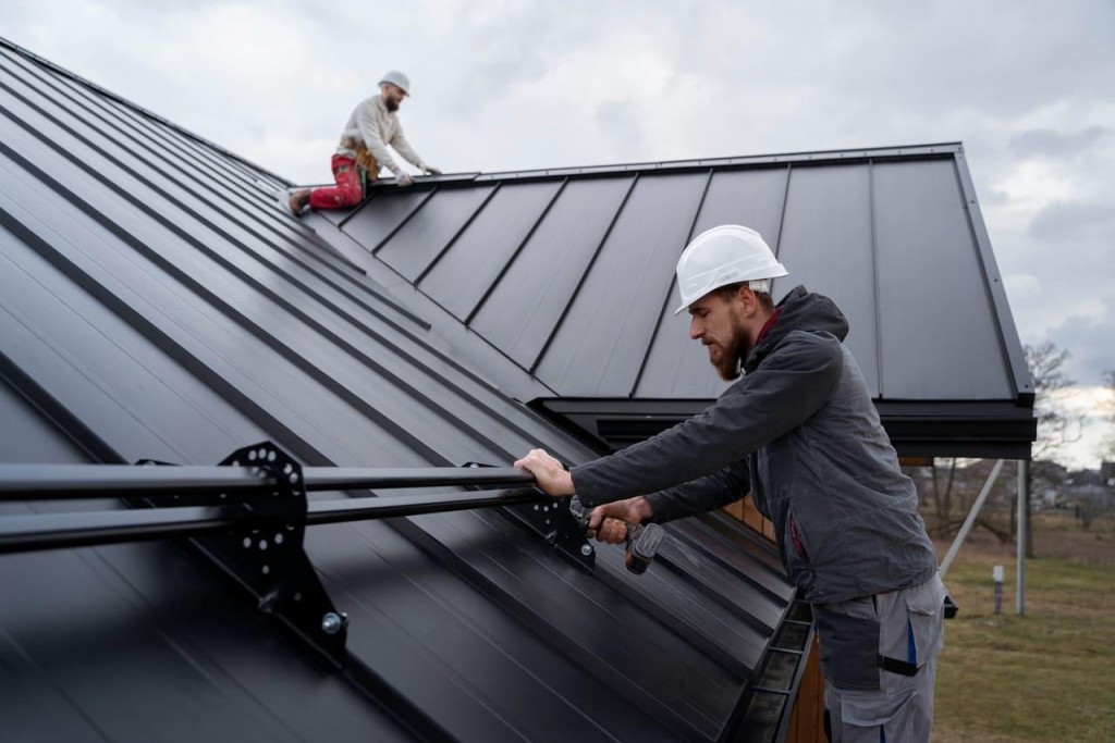 Roofing contractors installing a standing seam metal roof and securing rooftop mounting hardware during a residential roofing project.